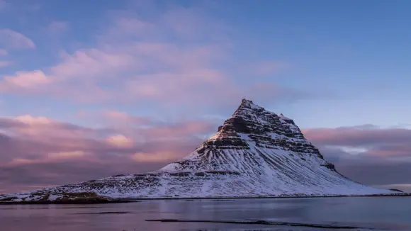 Kirkjufell Mountain, Iceland, covered in snow at sunrise.